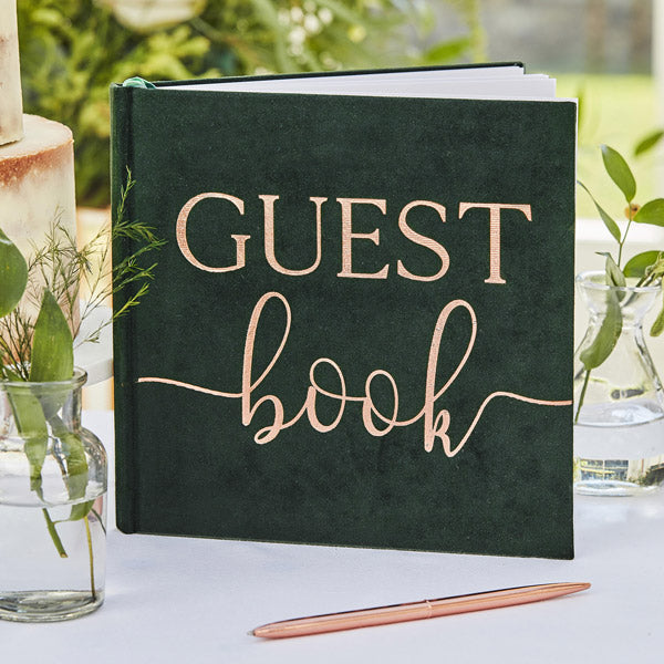 Grön gästbok i grön velour med texten GUEST book skrivet i guld.