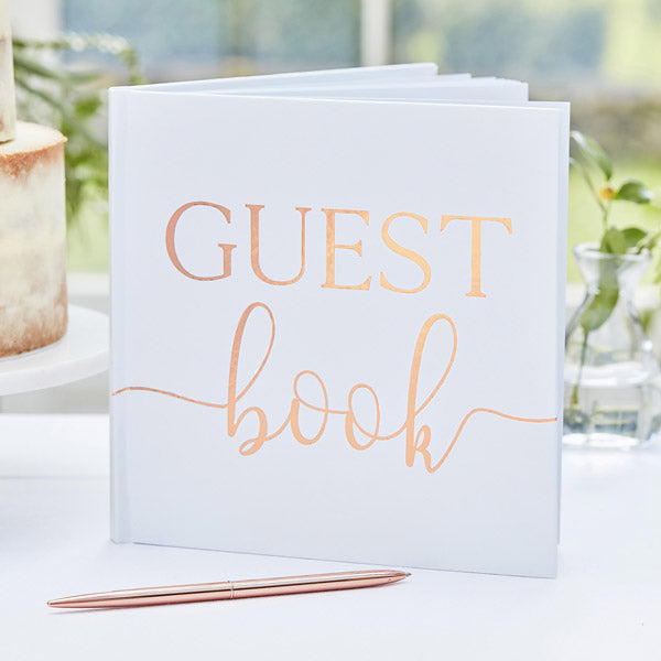 Vit gästbok med GUEST book skrivet i guld på framsidan.